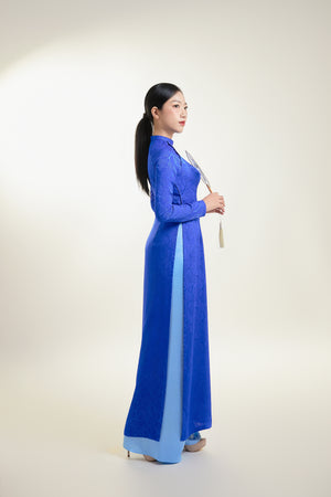 Elegant Thai Tuan silk brocade Ao Dai in blue with leaf pattern, side view.