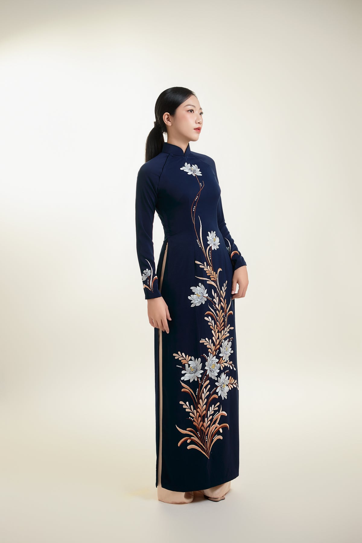 Elegant ao dai in dark blue silk with chrysanthemum embroidery, showcasing traditional Vietnamese fashion.