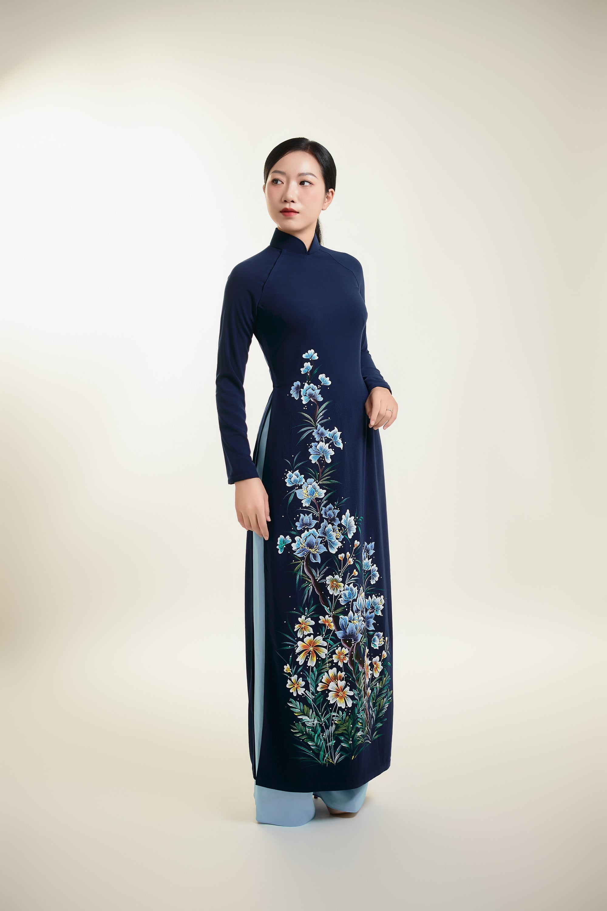 Elegant hand-painted Ao Dai on dark blue silk with floral design, full view.