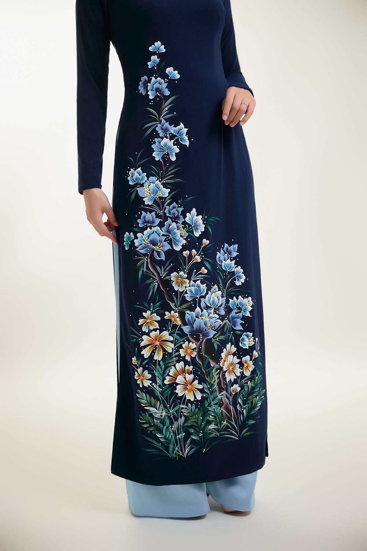Close-up of hand-painted floral design on dark blue silk Ao Dai.