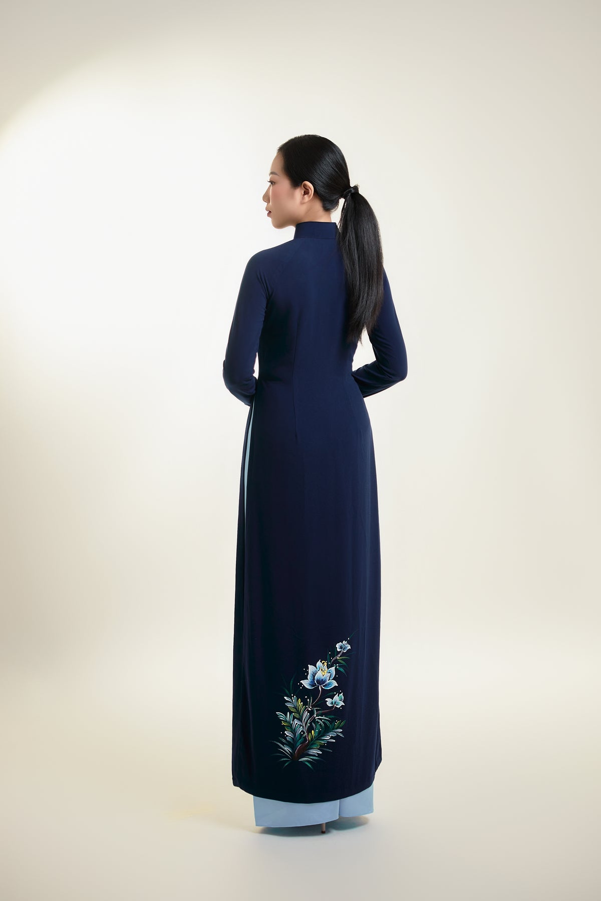 Back view of hand-painted Ao Dai on dark blue silk with subtle floral accents.