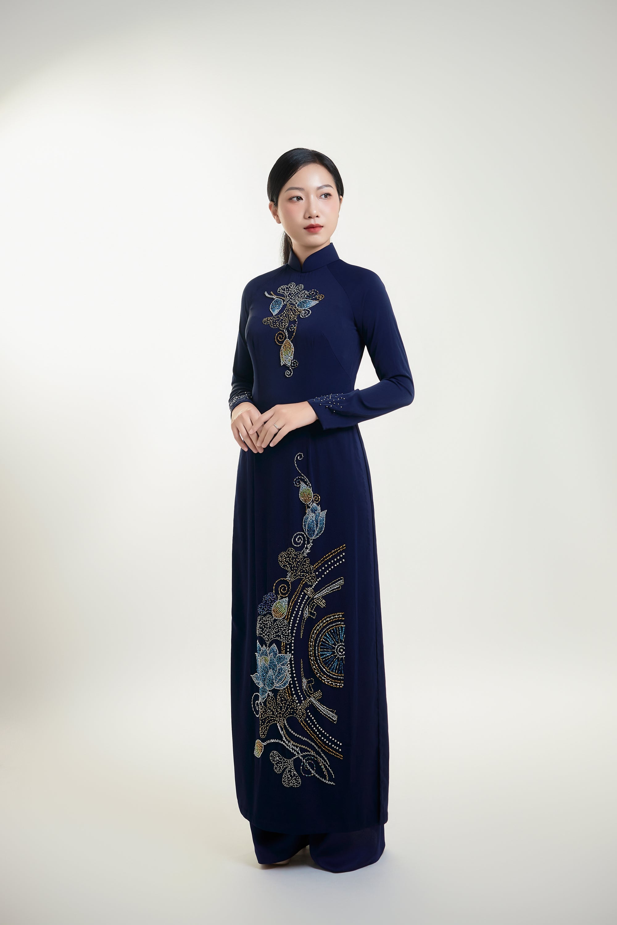 Traditional hand-beaded Ao Dai in navy blue featuring intricate Trong Dong and lotus designs, worn by a woman.