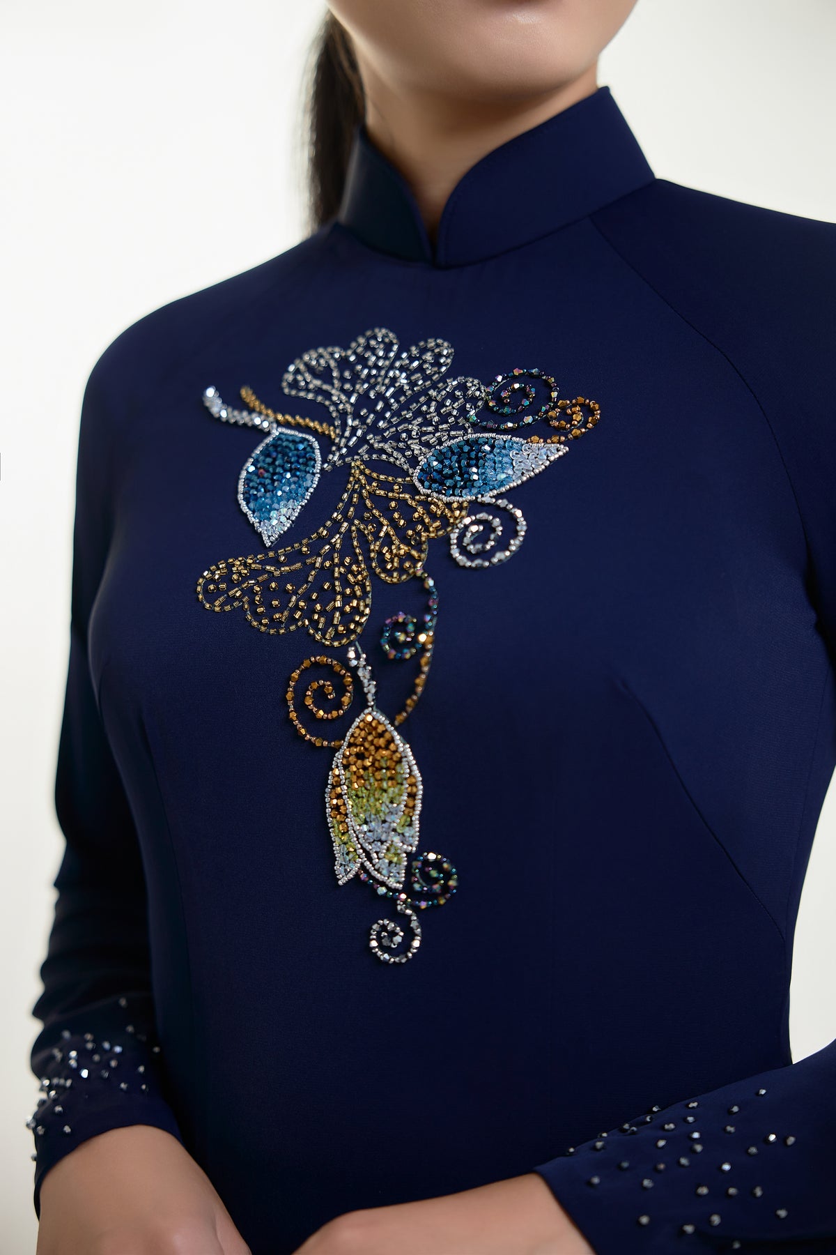 Intricate blue hand-beaded design on a traditional Ao Dai featuring floral motifs, celebrating Vietnamese cultural heritage.