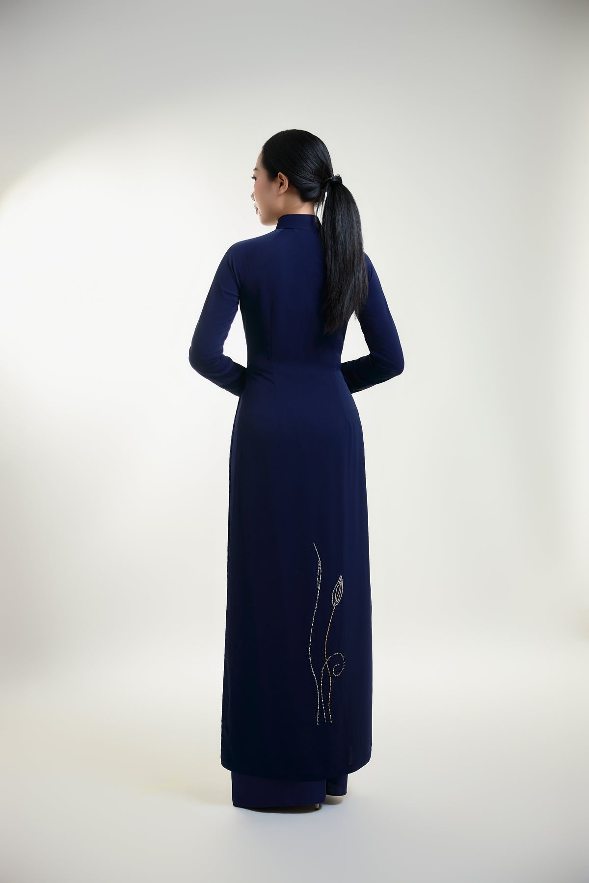 Traditional hand-beaded Ao Dai featuring intricate lotus designs, showcasing elegance and cultural heritage from the back view.